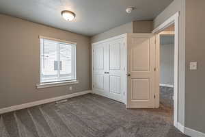 Unfurnished bedroom with carpet floors, a textured ceiling, and a closet