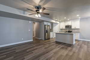 Kitchen with light stone countertops, appliances with stainless steel finishes, sink, white cabinets, and dark hardwood / wood-style floors