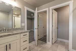 Bathroom with vanity, a shower with shower door, and a textured ceiling