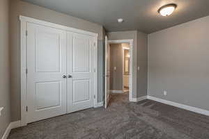 Unfurnished bedroom with dark colored carpet, a textured ceiling, and a closet