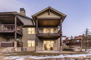 Snow covered rear of property with central AC and a balcony