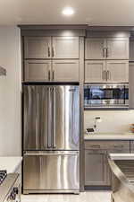 Kitchen with gray cabinets, backsplash, and appliances with stainless steel finishes