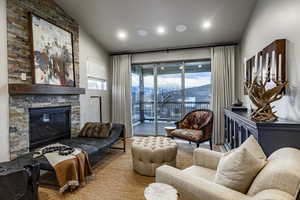 Living room with a mountain view, a fireplace, a healthy amount of sunlight, and vaulted ceiling