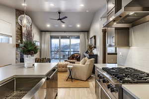 Kitchen with decorative backsplash, decorative light fixtures, extractor fan, and plenty of natural light