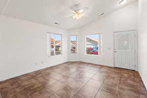 Tiled empty room featuring ceiling fan and vaulted ceiling