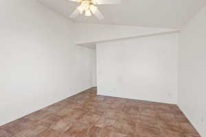 Unfurnished room featuring ceiling fan and lofted ceiling