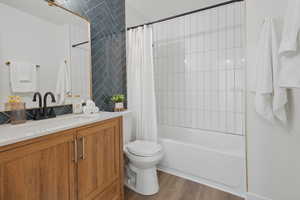 Full bathroom with toilet, hardwood / wood-style floors, vanity, and shower / tub combo with curtain