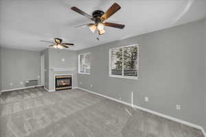 Unfurnished living room with ceiling fan, light colored carpet, and a wall mounted air conditioner