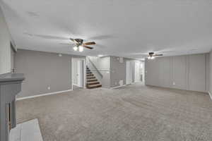 Unfurnished living room featuring a textured ceiling, ceiling fan, and light carpet