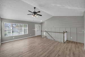 Bonus room with a textured ceiling, vaulted ceiling, light hardwood / wood-style flooring, and ceiling fan