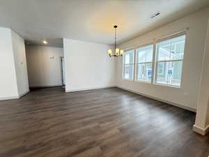 Unfurnished room featuring dark hardwood / wood-style flooring and a notable chandelier