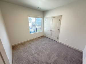 Unfurnished bedroom featuring a closet and light colored carpet