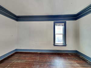 Unfurnished room with dark hardwood / wood-style flooring and ornamental molding