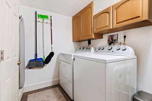 Clothes washing area with dark hardwood / wood-style flooring, cabinets, and washing machine and dryer