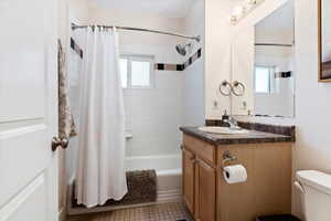 Full bathroom featuring tile patterned flooring, shower / tub combo, toilet, and a wealth of natural light