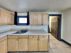 Kitchen with sink, light tile patterned flooring, and light brown cabinets