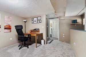 Carpeted home office featuring a textured ceiling