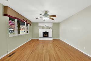 Unfurnished living room with ceiling fan, a fireplace, and hardwood / wood-style flooring