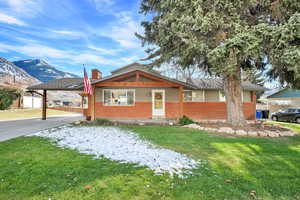 View of front of property featuring a carport, a mountain view, and a front lawn