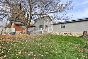 Rear view of property with a lawn and a wooden deck