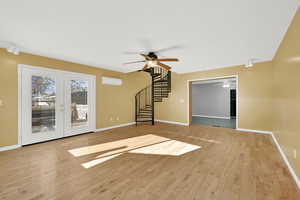 Unfurnished living room featuring french doors, light hardwood / wood-style flooring, and a wall mounted AC