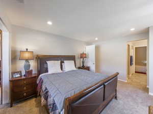 Bedroom featuring light colored carpet and ensuite bath