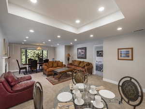 Carpeted living room featuring a tray ceiling and a chandelier