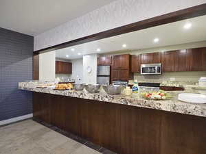 Kitchen featuring kitchen peninsula, appliances with stainless steel finishes, and light stone counters