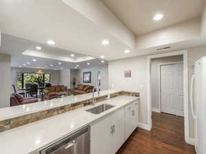 Kitchen featuring dishwasher, dark wood-type flooring, white refrigerator, sink, and a tray ceiling