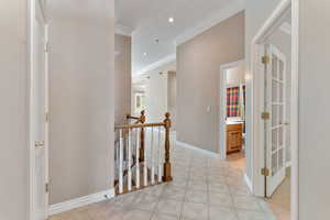 Hall featuring light tile patterned floors and ornamental molding