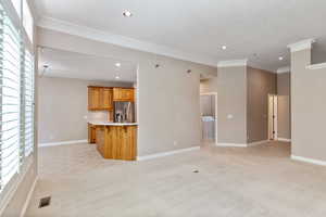 Unfurnished living room with light carpet and ornamental molding