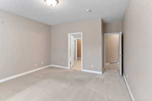 Unfurnished bedroom with light colored carpet and a textured ceiling