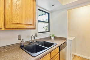 Kitchen featuring sink, stainless steel dishwasher, light tile patterned floors, a textured ceiling, and washer / clothes dryer