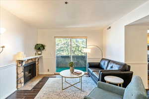 Living room with dark hardwood / wood-style floors and a stone fireplace