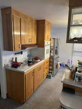 Kitchen with light carpet, stainless steel appliances, and a textured ceiling