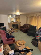 Carpeted living room with a stone fireplace and a textured ceiling