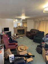 Living room with a fireplace, carpet floors, and a textured ceiling