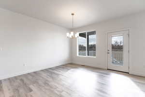 Unfurnished dining area with light hardwood / wood-style flooring and a notable chandelier