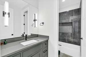 Bathroom with tiled shower, vanity, and toilet