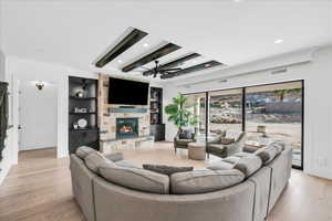 Living room with ceiling fan, a fireplace, light hardwood / wood-style floors, and built in features