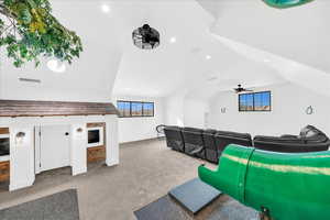 Carpeted home theater with ceiling fan and lofted ceiling