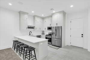 Kitchen featuring white cabinetry, sink, stainless steel appliances, a kitchen breakfast bar, and kitchen peninsula