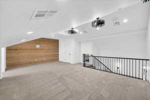 Bonus room featuring wood walls, light carpet, and vaulted ceiling