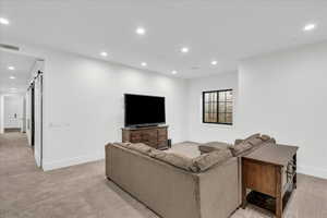 Living room with a barn door and light carpet