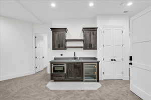 Bar featuring stainless steel oven, sink, wine cooler, light colored carpet, and dark brown cabinetry