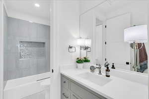 Full bathroom with vanity, tiled shower / bath combo, and toilet