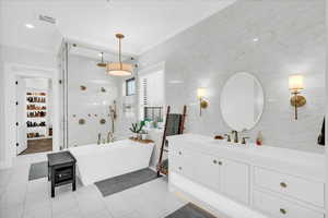 Bathroom with vanity, shower with separate bathtub, and tile walls