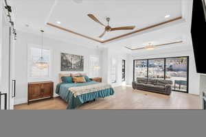 Bedroom featuring a tray ceiling, light hardwood / wood-style floors, and ceiling fan with notable chandelier