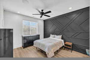 Bedroom with black refrigerator, light hardwood / wood-style flooring, and ceiling fan