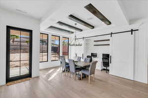 Dining space featuring a barn door, light hardwood / wood-style flooring, and an inviting chandelier